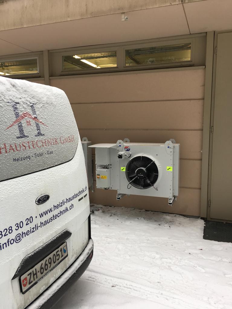 Firmenbus von Heizli Haustechnik mit Luftwärmepumpe im Hintergrund